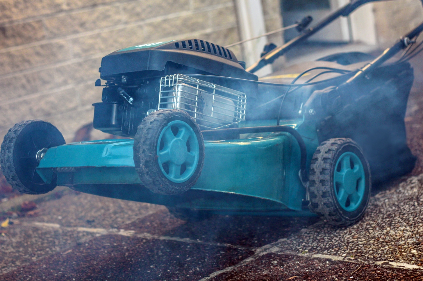 Lawn mower emitting white smoke while sitting on a driveway